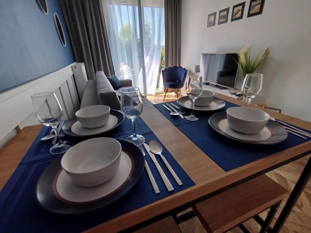 a dining room table with plates and wine glasses at Trimare Blue Apartament Sztutowo in Sztutowo