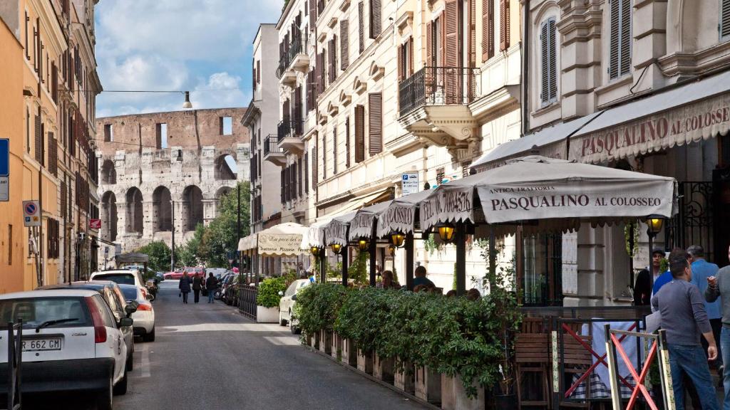 uma rua da cidade com edifícios e carros estacionados na rua em Rental in Rome Colosseo Loft em Roma
