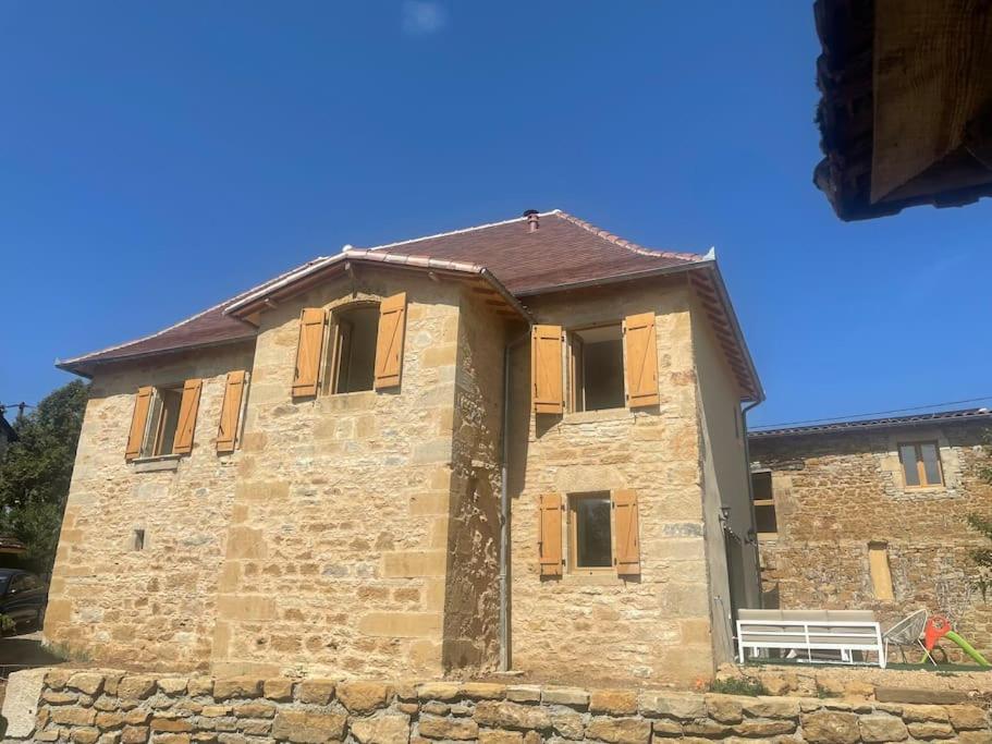 un edificio in pietra con una panchina di fronte di Gîte La Vacale- 2 à 10 personnes a Capendac