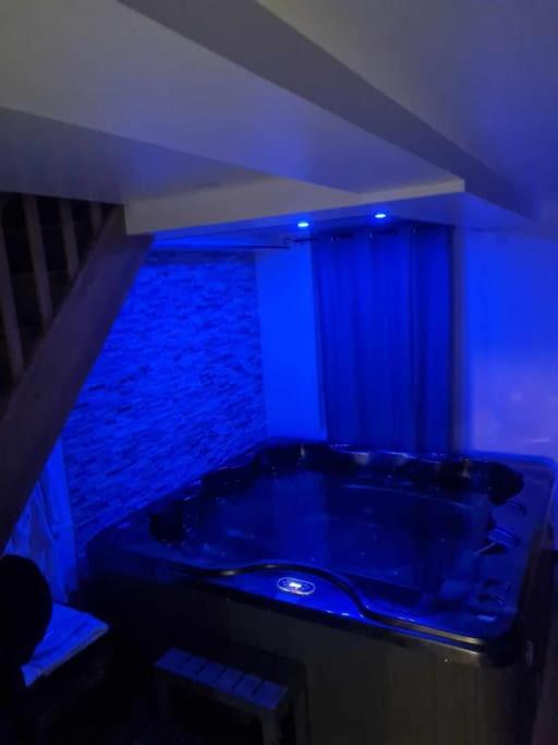 d'une baignoire dans une chambre à l'éclairage bleu. dans l'établissement Maison cosy avec jacuzzi, à Thourotte