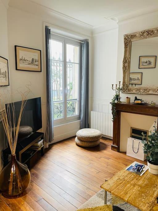 un salon avec une télévision et une cheminée dans l'établissement Charmant 2 pièces aux portes de Paris, à Levallois-Perret