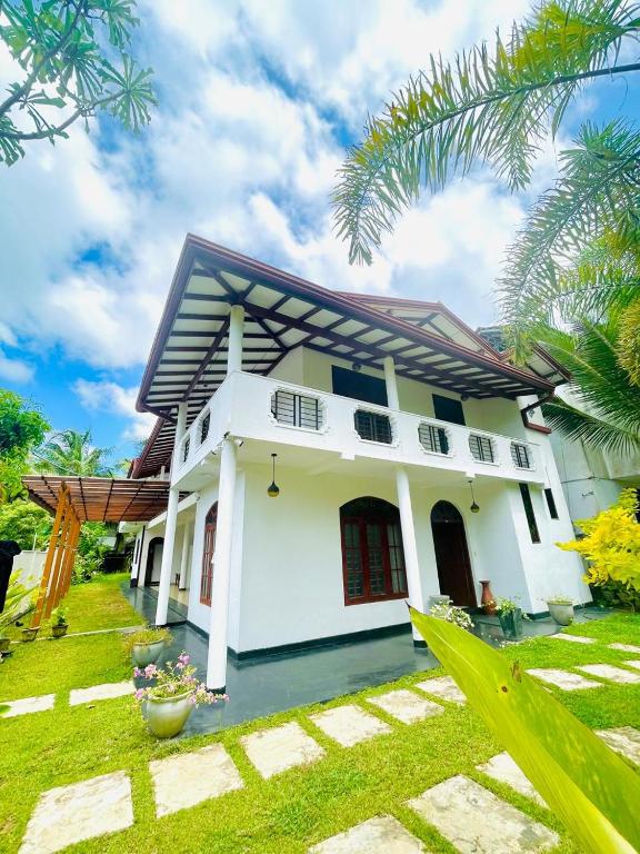 ein Haus mit einem grünen Rasen davor in der Unterkunft White Horse in Hikkaduwa