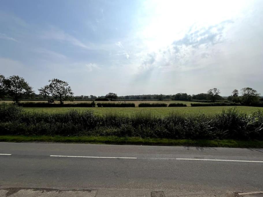 eine leere Straße neben einem Grasfeld in der Unterkunft Fern Cottage in Brinklow