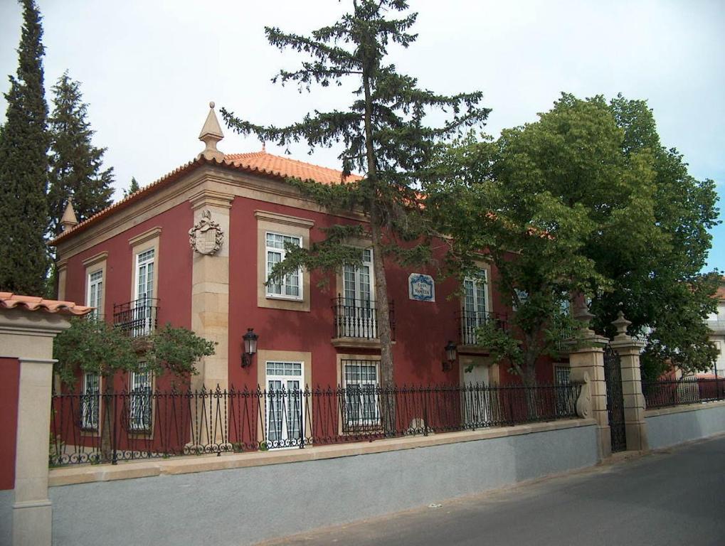 un bâtiment rouge avec une clôture devant lui dans l'établissement Falcao de Mendonca, à Figueira de Castelo Rodrigo