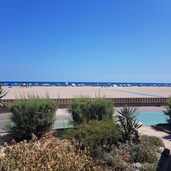 une passerelle à côté d'une plage avec une jetée et des buissons dans l'établissement Joli petit pavillon climatisé 50 m de la mer, à Saint Pierre La Mer