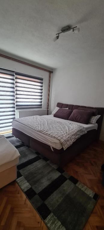 a bedroom with a large bed in a room with windows at Apartman Dženix in Sarajevo