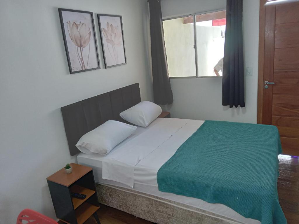 a bedroom with a bed with a green blanket and a window at kitnet com garagem exclusiva in Venda Nova
