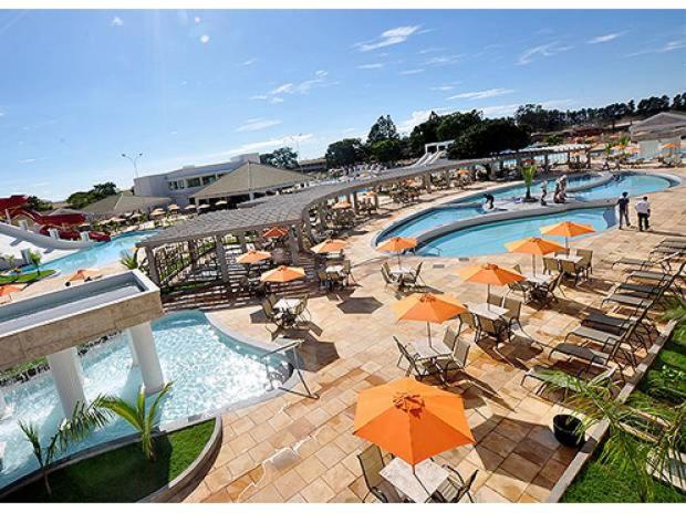 uma grande piscina com guarda-sóis e pessoas num resort em Park L'acqua di roma - Cozinha completa em Caldas Novas