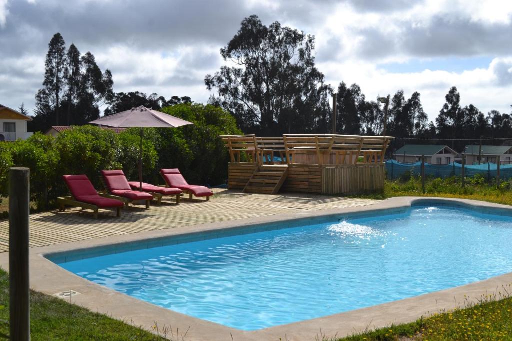 a swimming pool with lounge chairs and an umbrella at Cabañas Boutique il Bosco in Algarrobo