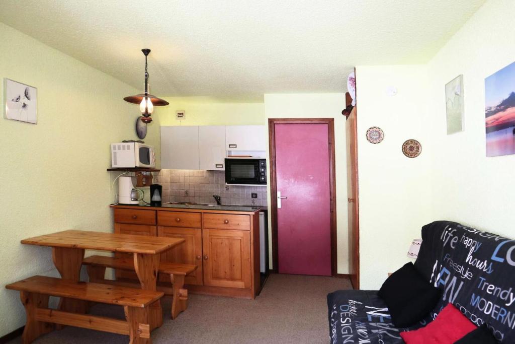 une cuisine avec une table et une porte violette dans l'établissement Résidence Le Cairn - Résidence Cairn - Studio 4 personnes vue pistes MAE-6351, aux Orres