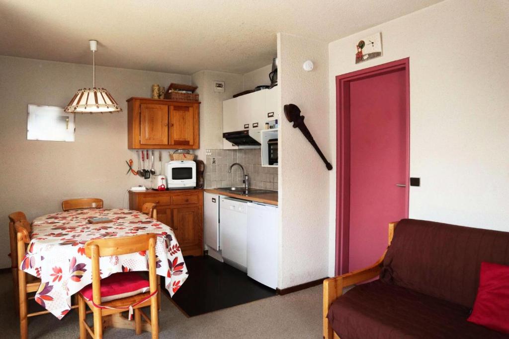 une petite cuisine avec une table et une porte rouge dans l'établissement Résidence Le Cairn - APPARTEMENT 6 PERSONNES N° 506 CAIRN MAE-6341, aux Orres