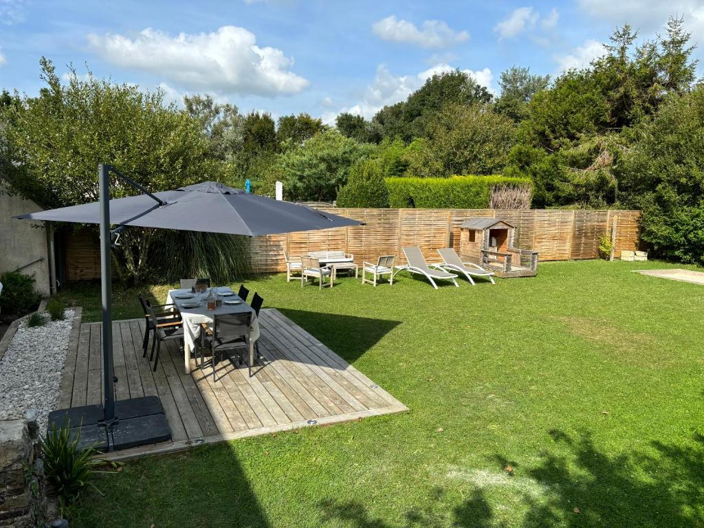 un patio avec une table et un parasol dans une cour dans l'établissement Maison Portbail sur Mer, à Denneville