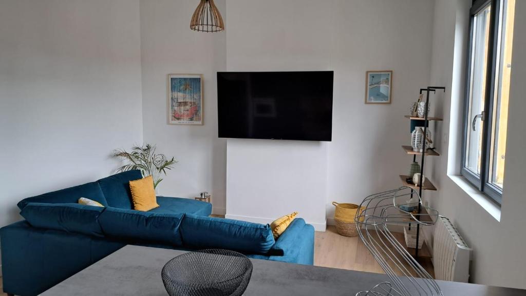 a living room with a blue couch and a flat screen tv at Appartement Miami près de Douai in Flers-en-Escribeus