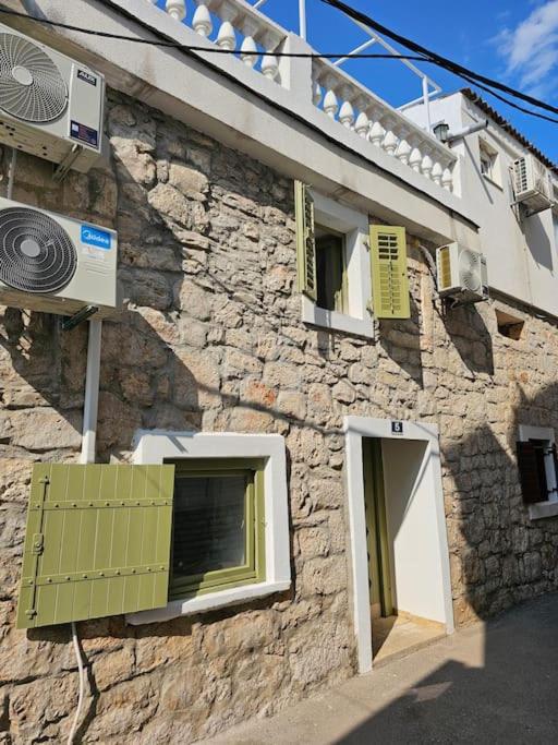 a stone building with two windows and a fan at Stone Three bedroom house with rooftop terrace in Jezera