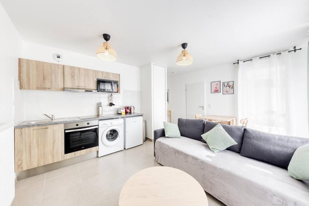 ein Wohnzimmer mit Sofa und eine Küche in der Unterkunft L'Elégant de Paris - Villepinte - Paris in Villepinte
