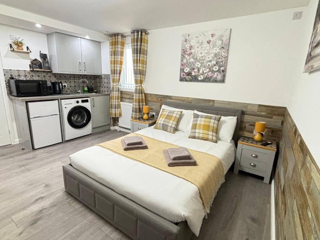 a bedroom with a large bed and a kitchen at Gatwick Lodge in Horley