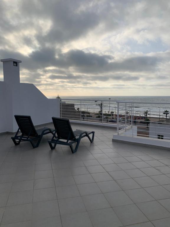 two chairs on a roof with the ocean in the background at Villa Jackbeach front mer in Dar Bouazza