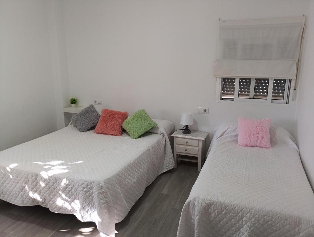 two beds with colorful pillows in a bedroom at El Recuerdo in Arcos de la Frontera