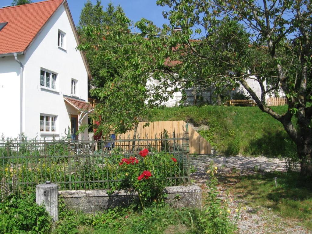 una casa blanca con una valla y flores en Ferienhaus am Lech, en Kaufering