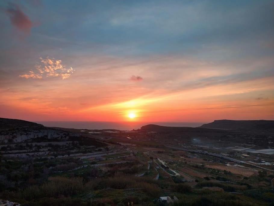 a sunset with the sun setting over a city at Peaceful 2 bed, 2 bath flat & breathtaking views in Mellieħa