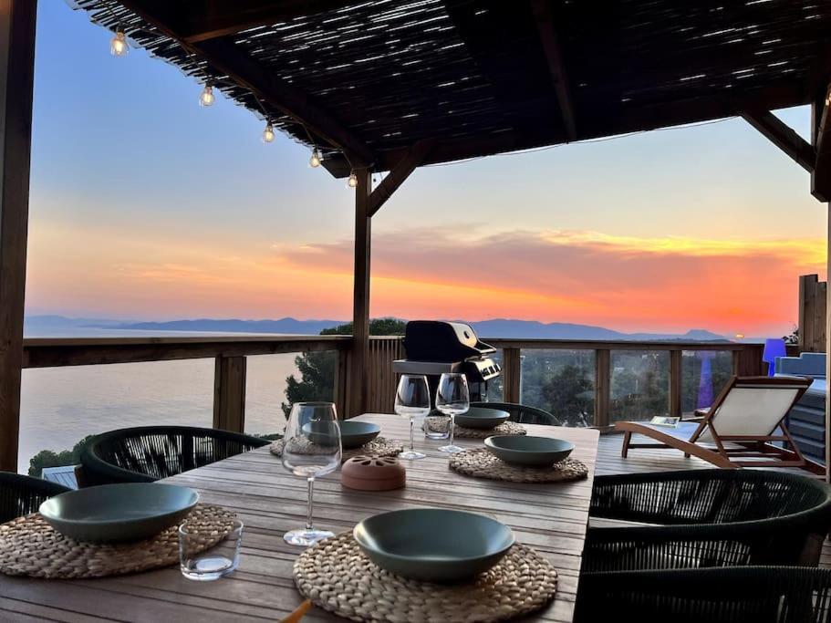 - une table en bois avec des assiettes et des verres à vin sur une terrasse dans l'établissement Mobil home vue exceptionnelle et spa - Domaine de l'Ile d'Or, à Saint-Raphaël
