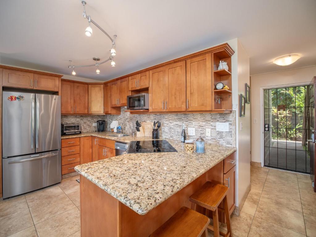 a kitchen with wooden cabinets and a granite counter top at WBH D116 Aloha Wai - Garden Suite Just Steps from the Sea in Kihei