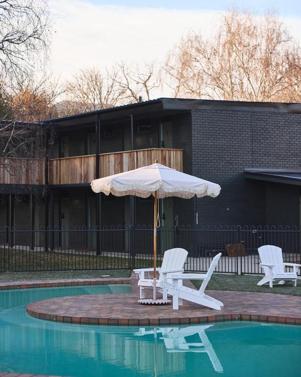 an umbrella and two chairs sitting next to a pool at Alpine Inn in Khancoban