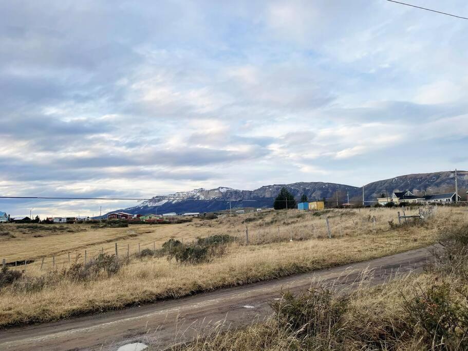 a road in a field with mountains in the background at Casita Hello! in Puerto Natales
