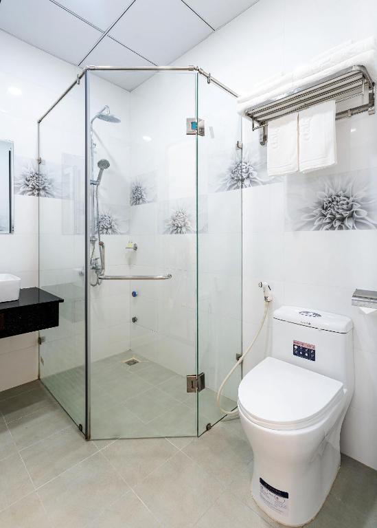 a bathroom with a toilet and a glass shower at Dalat Wind Hotel in Da Lat