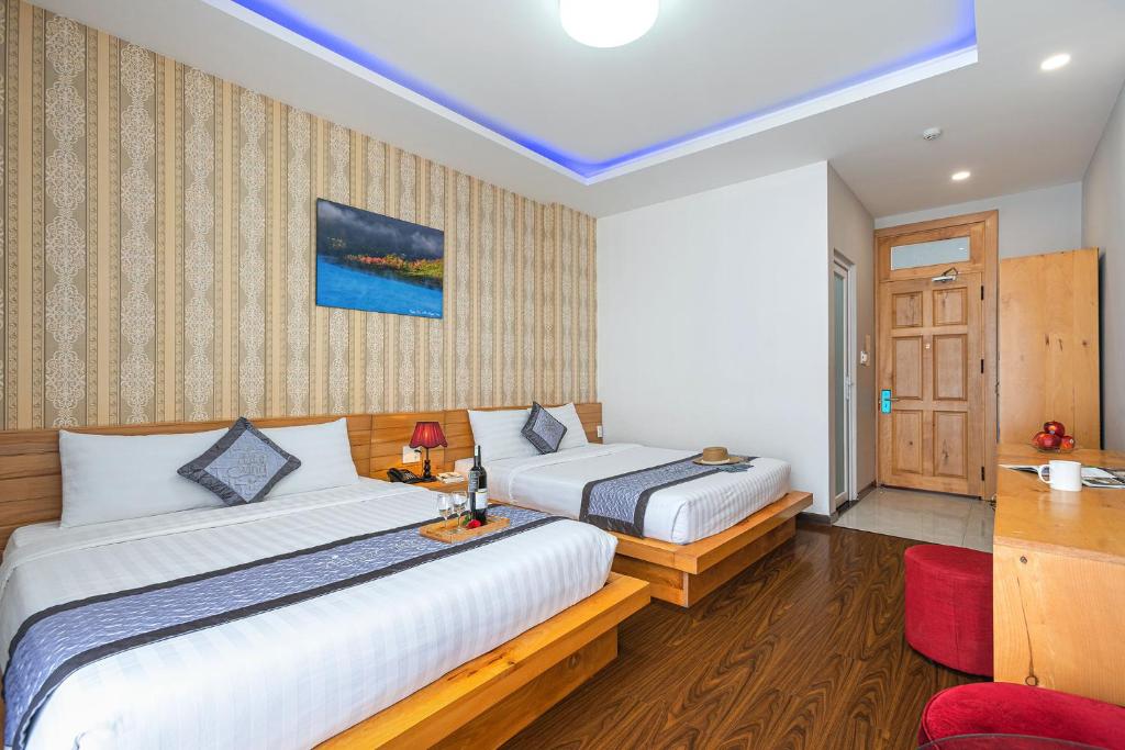 a bedroom with two beds and a desk in it at Dalat Wind Hotel in Da Lat