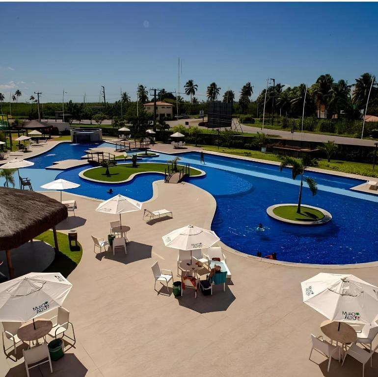 una vista sul tetto di una piscina con ombrelloni e tavoli di Lazer - Flat Condomínio Muro Alto Clube a Porto De Galinhas