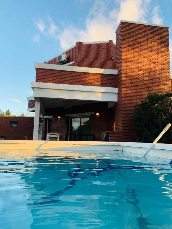 a house with a swimming pool in front of a building at Las Moras casa de campo en Lobos in Lobos