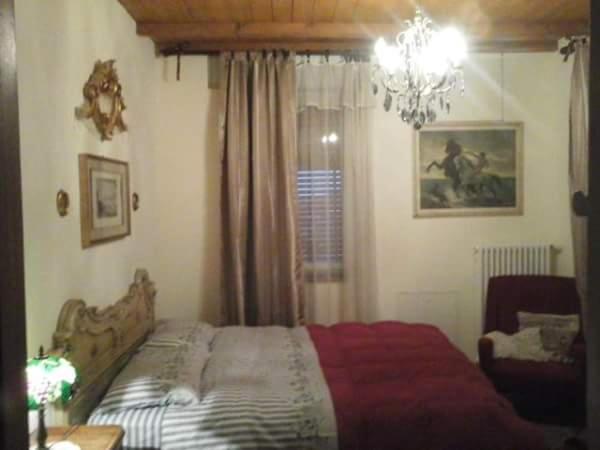 um quarto com uma cama e um lustre em B&B CM Ranch em Cuneo