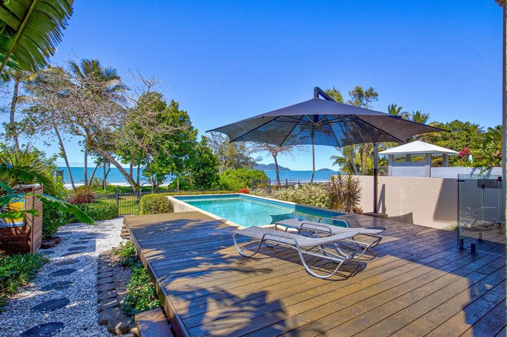 - Piscina con sombrilla, silla y sombrilla en Frangipani Place - Absolute Beachfront, en South Mission Beach