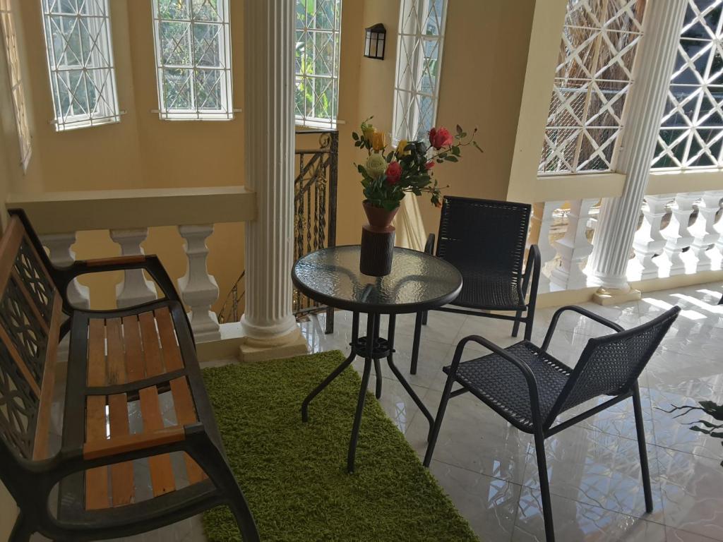 una mesa y sillas en una habitación con ventanas en Cazwin Villas en Montego Bay