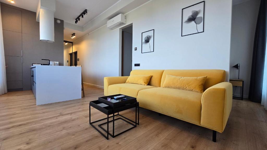 Una sala de estar con un sofá amarillo y una mesa. en Artisa Riia Str 20a Luxury Penthouse Apartment, en Tartu