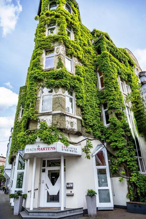 a building covered in green ivy at Hotel Haus Martens in Hannover