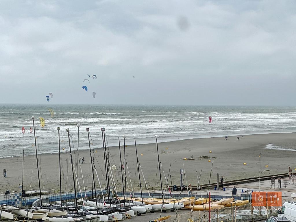 une plage avec des gens volant des cerfs-volants dans l'océan dans l'établissement Le Sunset - Face mer, à Wimereux