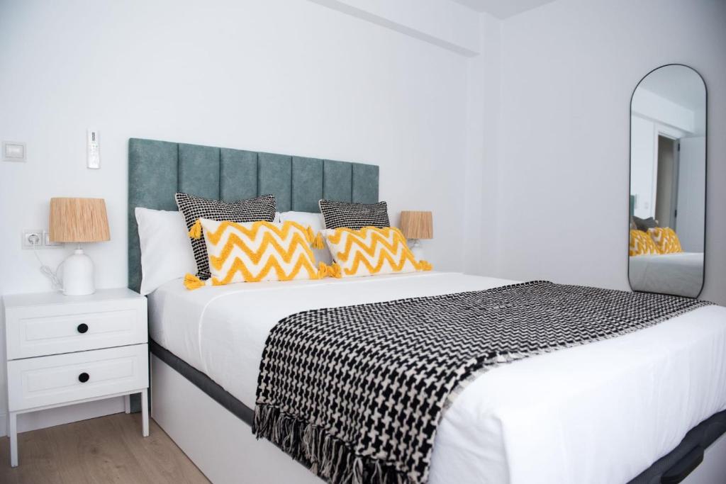 a bedroom with a large white bed and a mirror at La Deliciana in Zaragoza