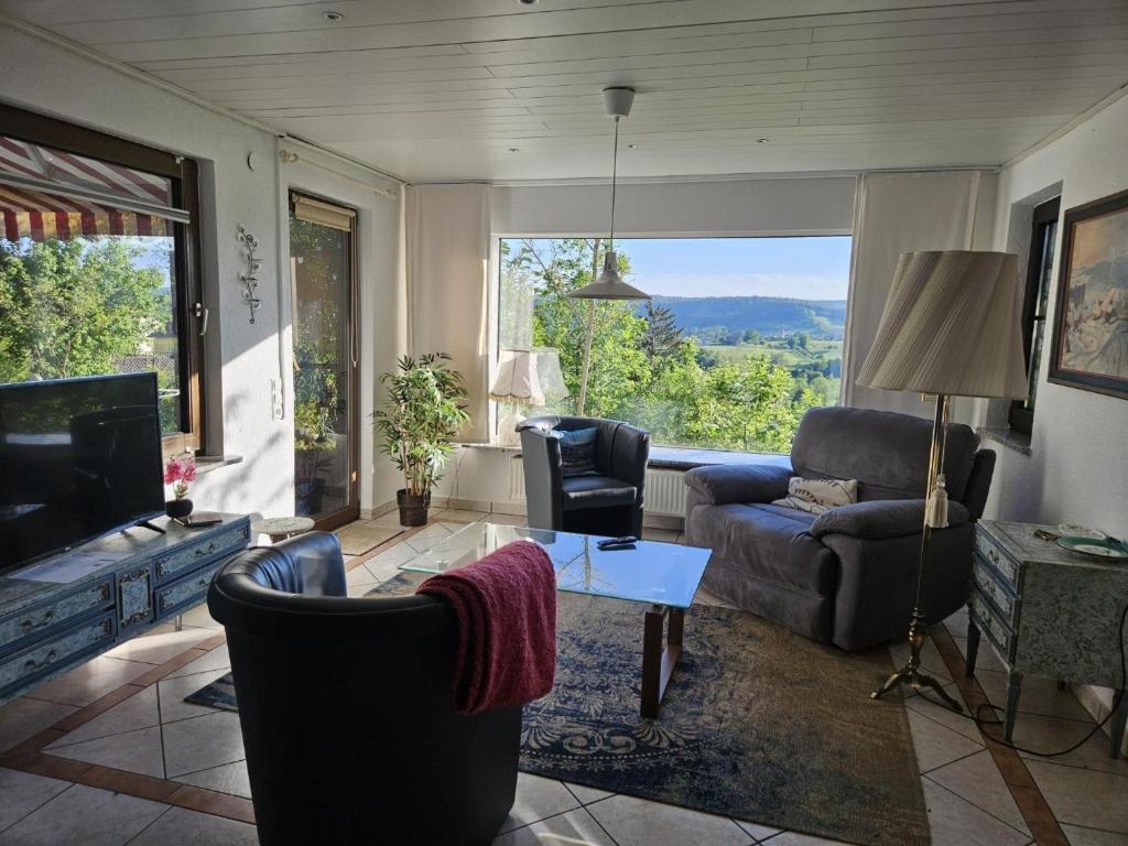 ein Wohnzimmer mit einem Sofa, Stühlen und einem TV in der Unterkunft Ferienwohnung Unter Linden in Bad Bocklet