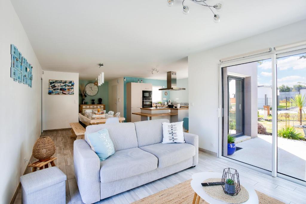 un salon avec un canapé et une cuisine dans l'établissement Maison moderne avec jardin - 5min de la plage, à Erquy