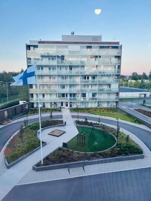 埃斯波Aurora Home Espoo Niittykumpu - New 1bedroom -apartment with balcony, close to metro, Aalto University, Metro Areena and Helsinki的一座大型建筑,前面有一个公园