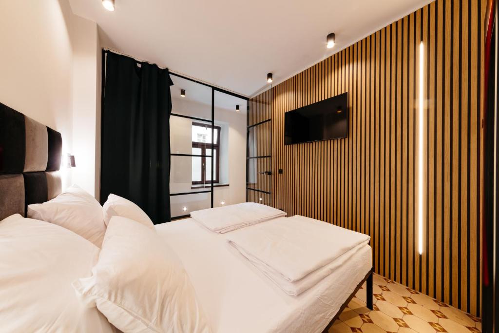 a bedroom with a white bed and a tv on a wall at Main Square Rooms in Maribor