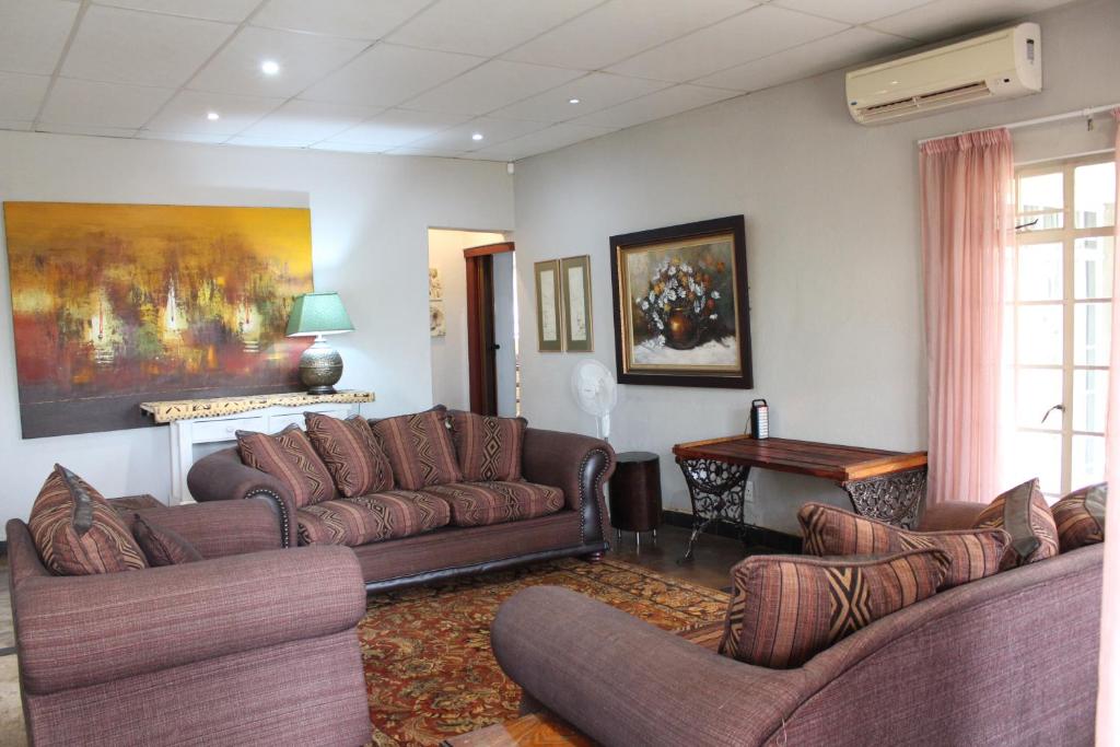 a living room with couches and a table at Tucked-Away 1&2 Bedroom Houses in Nelspruit