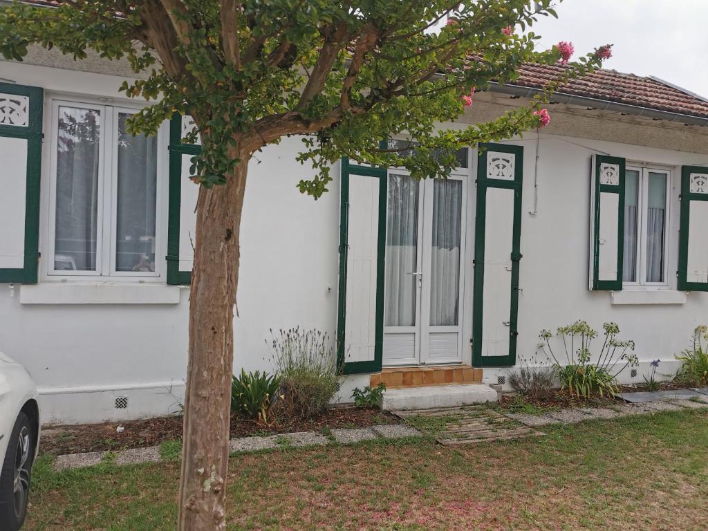 une maison blanche avec des fenêtres vertes et un arbre dans l'établissement MAISON T4 style ARCACHONNAISE, à Gujan-Mestras
