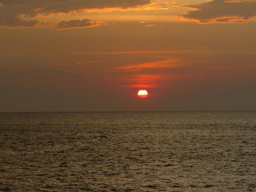 una puesta de sol sobre el océano con el sol en el cielo en Magia frente al Mar Caribe, en Cartagena de Indias