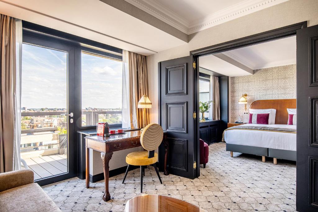 a hotel room with a desk and a bed and a window at Hotel Barsey by Warwick in Brussels
