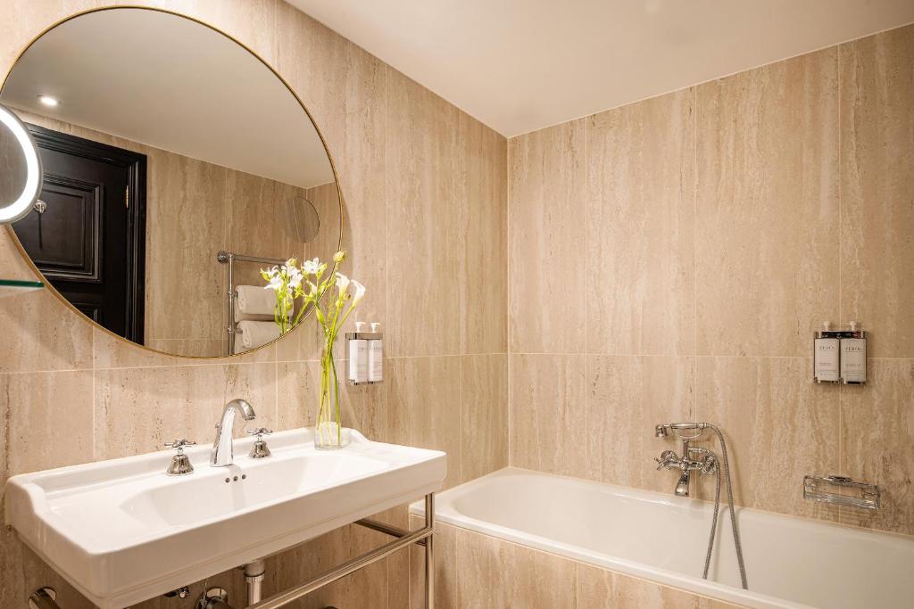 a bathroom with a sink and a tub and a mirror at Hotel Barsey by Warwick in Brussels