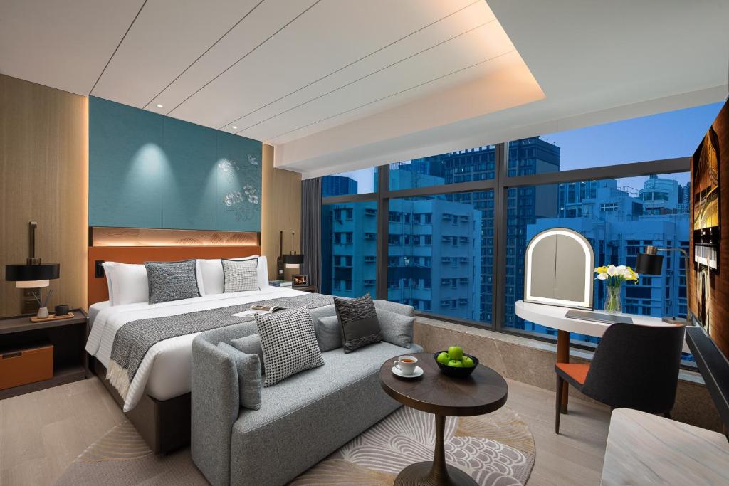 sypialnia z łóżkiem, kanapą i dużym oknem w obiekcie Ascott North Point Hong Kong w Hongkongu