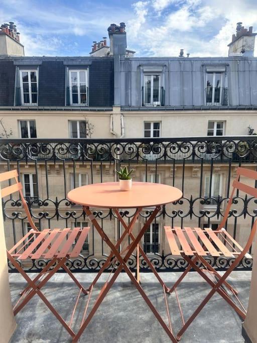 une table et deux chaises sur un balcon dans l'établissement Belleville, à Paris